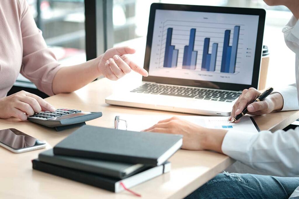 A person reviewing a savings account statement with a calculator and notepad on a wooden table.